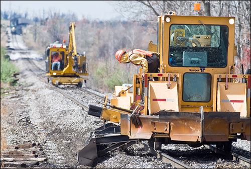 Francisco Morales Morado with Colo Railroad Builders of Geneseo, IL, leans out to check his equipment as he works on smoothing out ballast on Paducah and Louisville RailroadsÕ Warrior Coal spur off of A. C. Slaton Road Tuesday afternoon in Madisonville. P&LÕs loaded Louisville Gas and Electric coal train waits in the background for them to finish so it can move itÕs load north. The railroad is doing routine tie replacement along its line between Paducah and Louisville. (Photo/Jim Pearson)