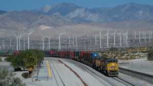 Union Pacific train KLBNS 21 (Priority Intermodal; Long Beach CA - Shreveport LA) passes by the Amtrak station in western Palm Springs, California, hidden away among the trees alongside the sand-covered track on the left. UP SD70ACe 8754 is leading AC4400CW 6526 and ES44AC 8013 as the train threads its way through the hundreds of wind turbines that dot San Gorgonio Pass. Once in Shreveport, this train is handed off to the Norfolk Southern to continue on to Atlanta, Georgia.